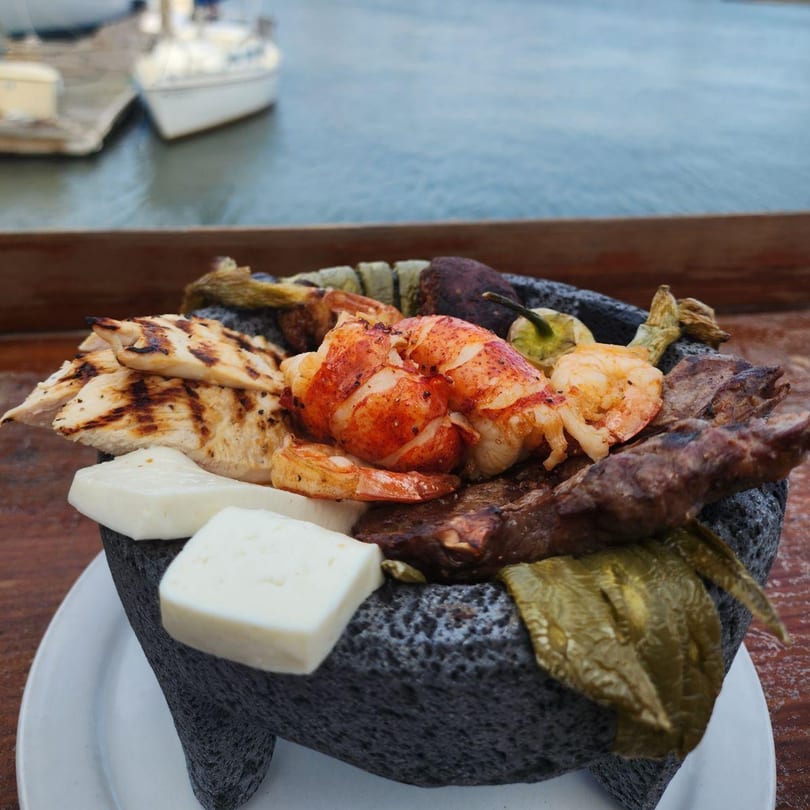 El Camaron Italiano's seafood platter with lobster, shrimp, chicken, and cheese, by the water.